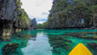 riding kayak in turquoise blue green water of big lagoon in el nido palawan