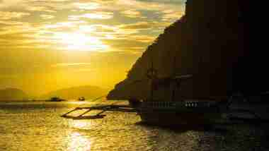 sunset view with boat in marimegmeg beach el nido palawan